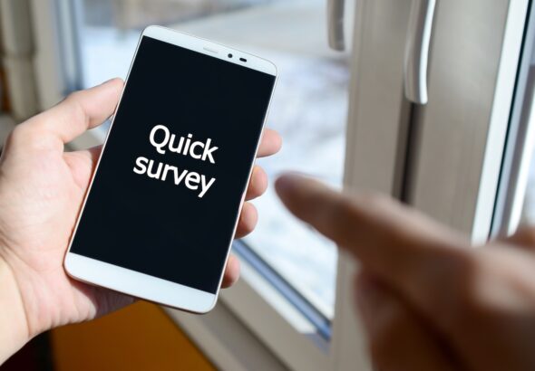 A person sees a white inscription on a black smartphone display that holds in his hand. Quick survey